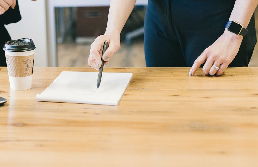 Manos señalando un cuaderno de planificación sobre una mesa